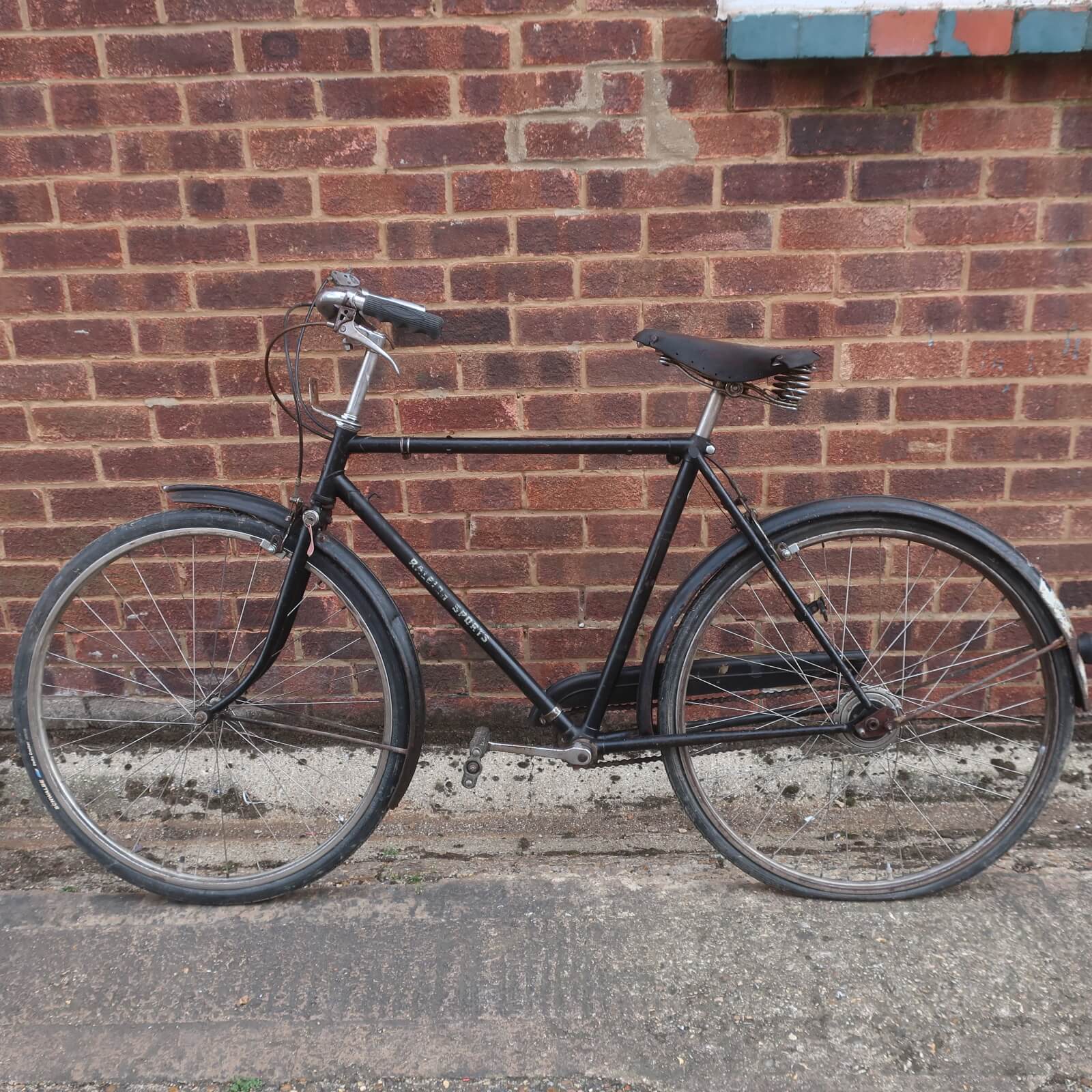 Black Raleigh step-through bicycle with fenders.