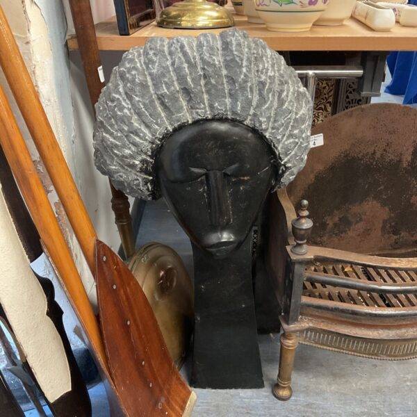 Stone or wood sculpture of a head with a large hat.